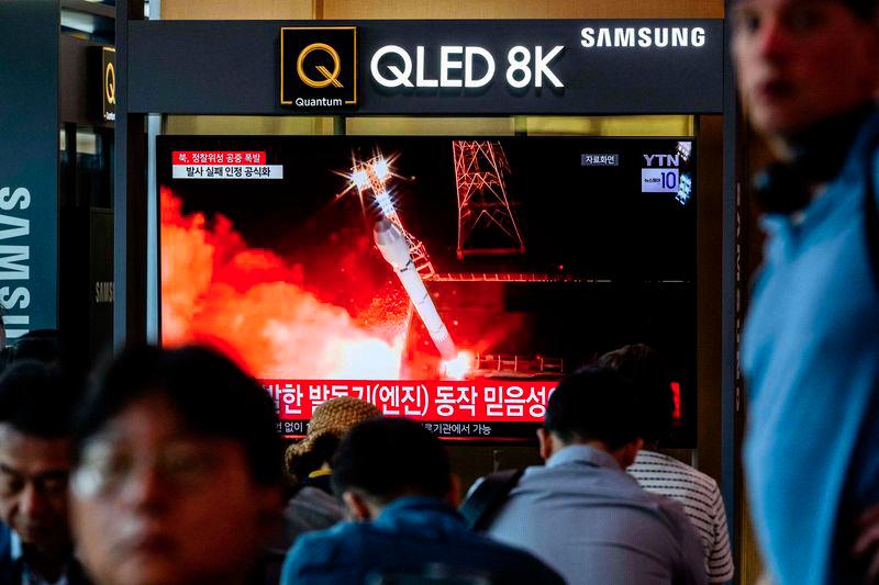 People sit near a television showing file footage during a news report at a train station in Seoul on May 28, 2024, after North Korea said late Monday that the rocket carrying its Malligyong-1-1 reconnaissance satellite exploded minutes after launch due to a suspected engine problem. - AFPPIX