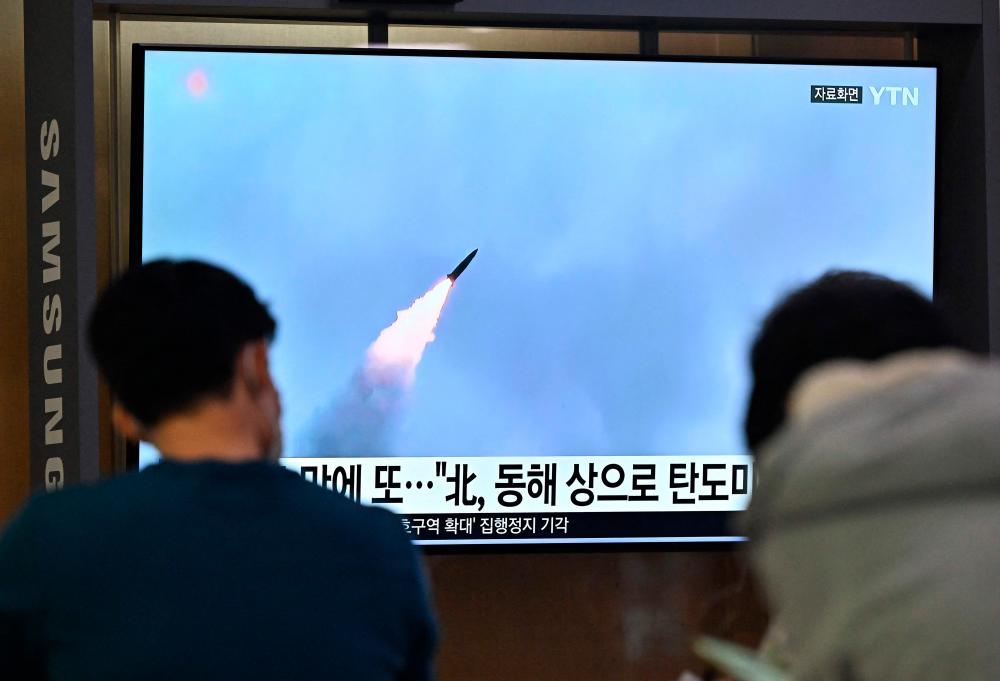 People watch a television screen showing a news broadcast with file footage of a North Korean missile test, at a railway station in Seoul on September 29, 2022. AFPPIX