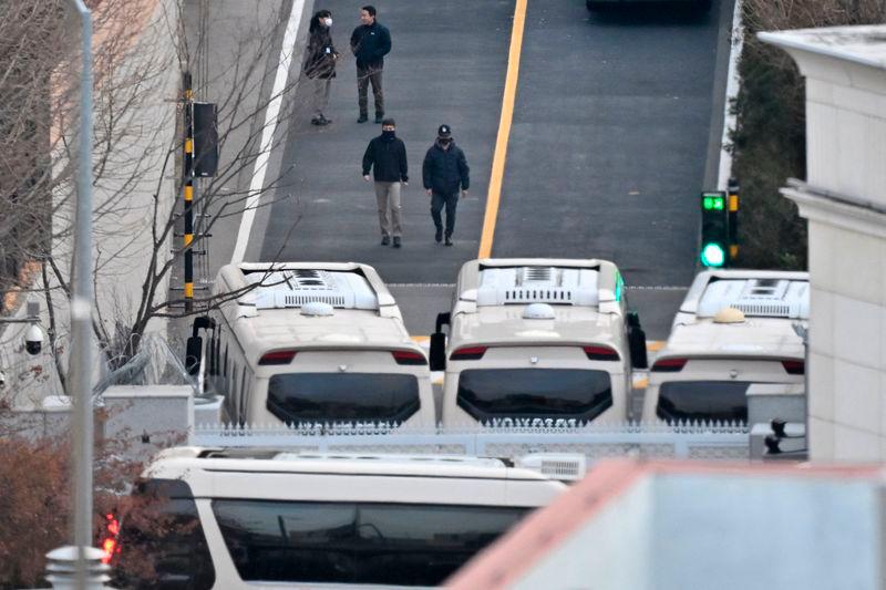 Security personnel walk on a road lined up with buses blocking the entrance gate to protect impeached South Korean president Yoon Suk Yeol - AFPpix