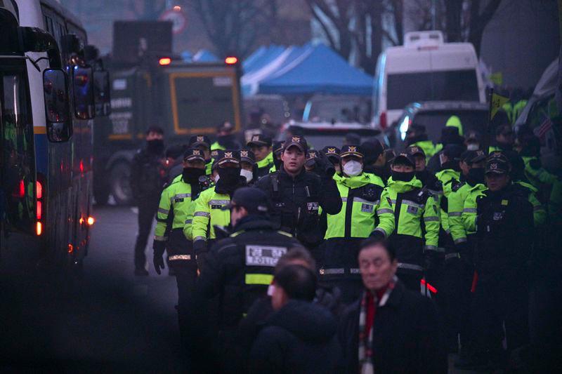 Police are seen between their parked vehicles on the road outside the residence of South Korea's impeached President Yoon Suk Yeol in Seoul early on January 6, 2025. - AFPPIX