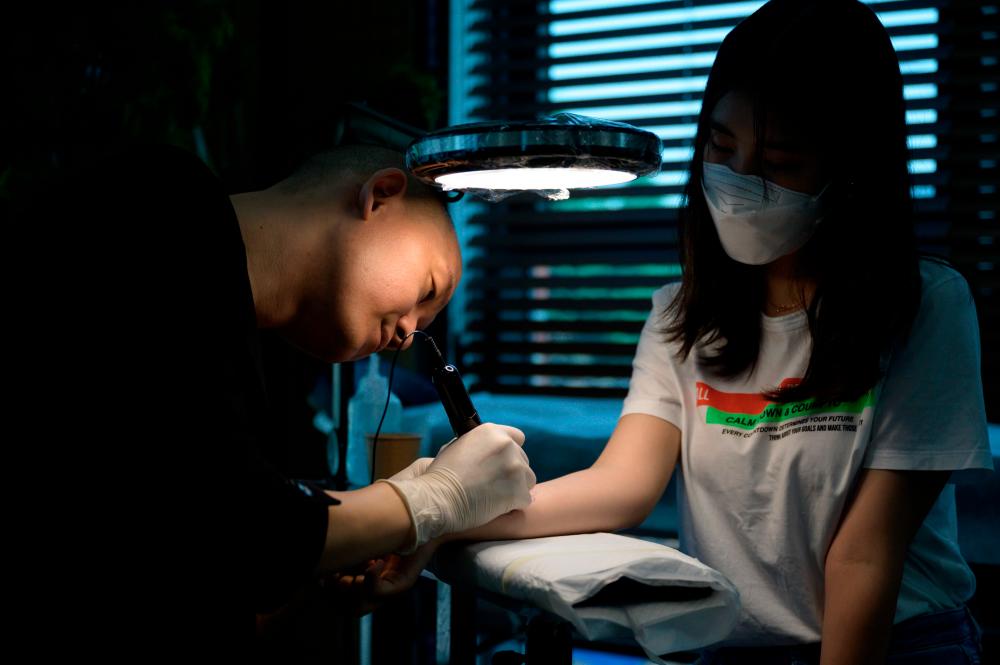 $!In a photo taken on July 8, 2020 tattoo artist Doy works on a client at his studio in Seoul. South Korean tattooist Doy counts Hollywood superstar Brad Pitt and members of K-Pop band EXO among his celebrity clients, but his delicate, detailed designs could land him in prison. / AFP / Ed JONES