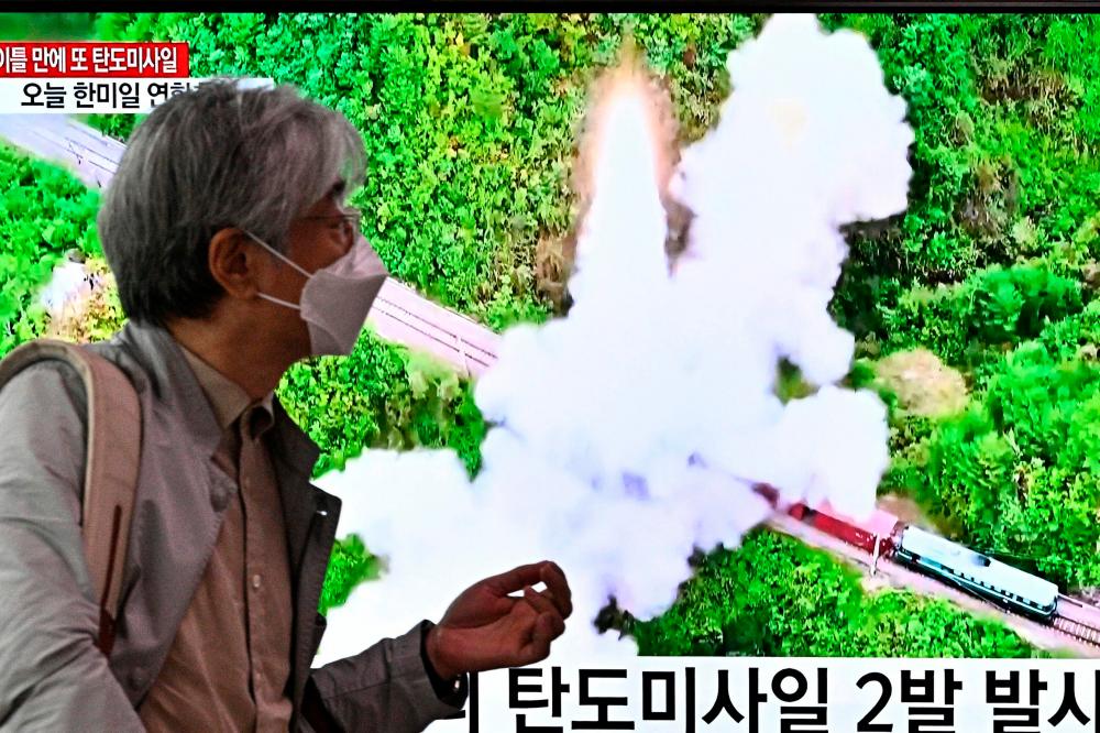 A man walks past a television report showing a news broadcast with file footage of a North Korean missile test, at a railway station in Seoul on October 6, 2022. AFPPIX
