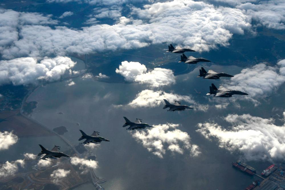 This handout photo taken on October 4, 2022 and provided by the South Korean Defence Ministry in Seoul shows four South Korean Air Force F-15Ks and four US Air Force F-16 fighters flying over South Korea, during a precision bombing drill in response to North Korea firing an Intermediate Range Ballistic Missile over Japan. - AFPPIX