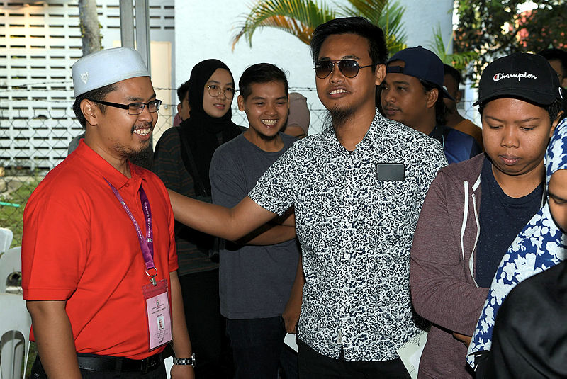 PSM candidate Nik Aziz Afiq Abdul (L) mingles with voters after casting his ballot and the Semenyih Community Hall, on March 2, 2019. — Bernama