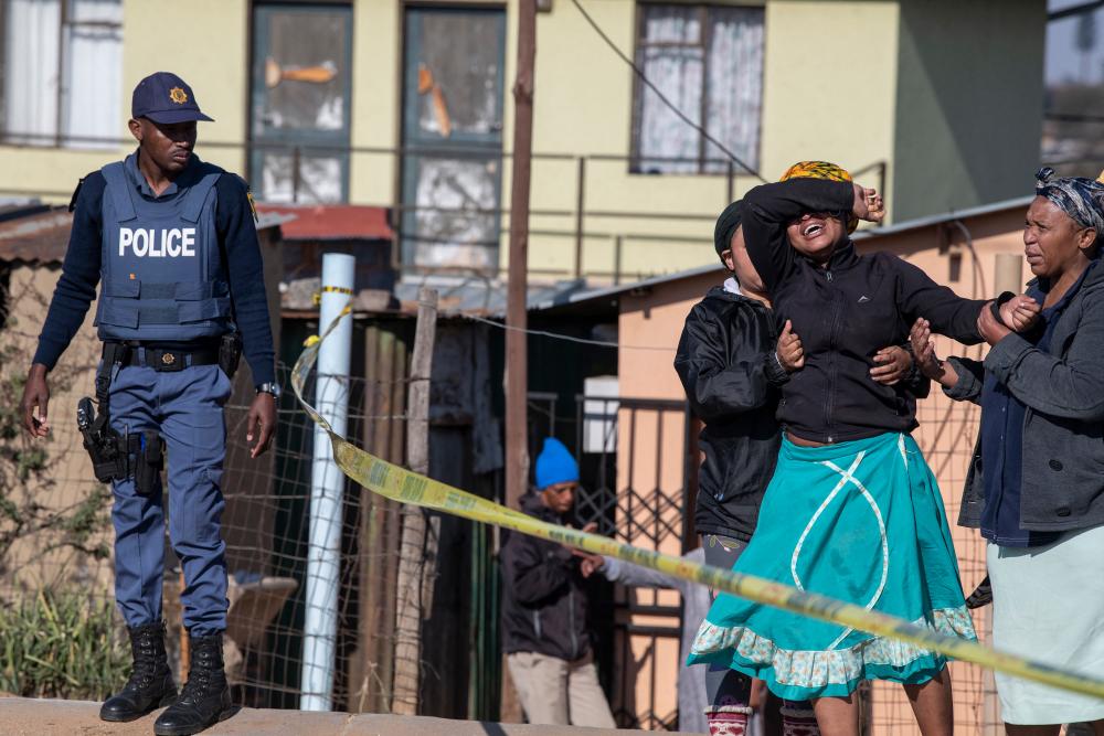 A relative of one of the victims cries as south African Police Service officers refuse to let her cross the police barrier and enter the crime scene in Soweto, South Africa, on July 10, 2022. AFPpix