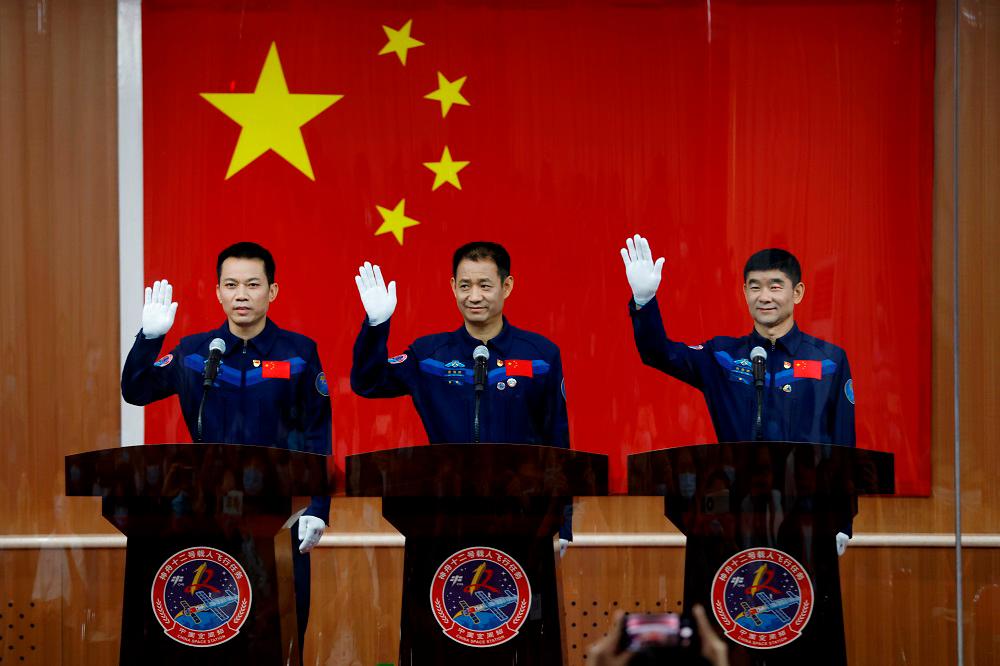 Chinese astronauts Nie Haisheng, Liu Boming, and Tang Hongbo wave as they meet members of the media behind a glass wall before the Shenzhou-12 mission to build China's space station, at Jiuquan Satellite Launch Center near Jiuquan, Gansu province, China June 16, 2021. -REUTERSPix