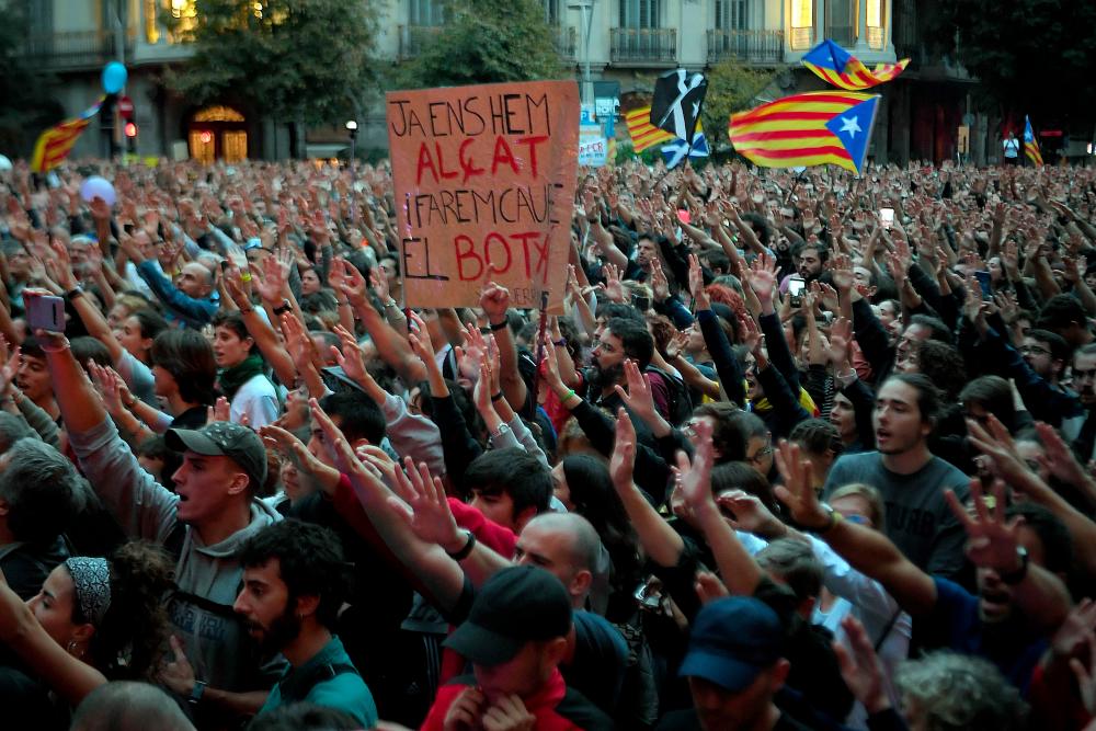 Protesterd hold a sign reading in Catalan We have already risen up and we will cause the execitioner's falldown during a protest called by Picnic for the Republic pro-independence movement outside the Spanish Government's regional office in Barcelona on Oct 20, 2019. — AFP