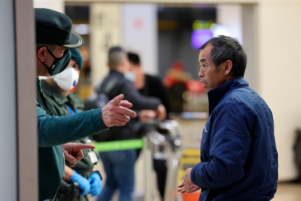 A passenger of a flight from Beijing listens to indications from a Civil Guard after landing at the Adolfo Suarez Madrid-Barajas airport in Barajas, on the outskirts of Madrid, on December 31, 2022/AFPPix