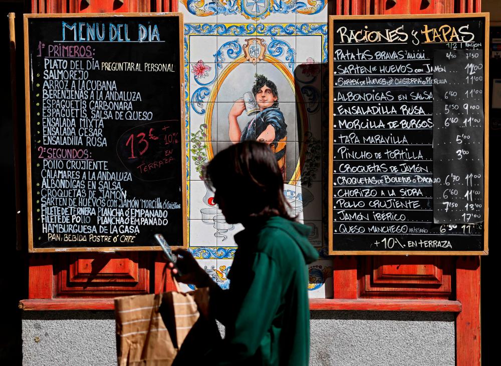 A pedestrian walks past a board showing today’s menu in the Spanish capital of Madrid, on September 5, 2022. AFPPIX