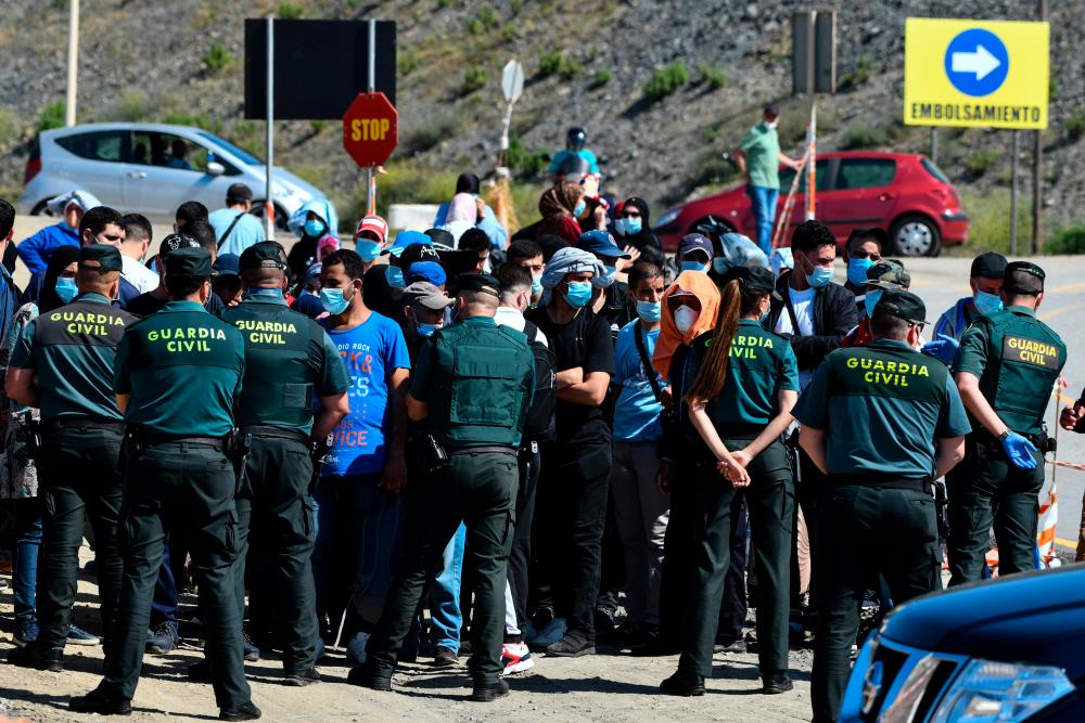 Moroccan citizens who will have to wait for their repatriation, after being stranded in Spain due to the coronavirus crisis, protest in front of police on May 22, 2020, in the Spanish enclave of Ceuta. About 300 Moroccan citizens, stranded in the Spanish enclave of Ceuta since Rabat closed its borders in mid-March to tackle the coronavirus, were repatriated today, authorities in Melilla said. The spokesman for the Spanish government in Ceuta indicated that, apart from those who are leaving today, around 150 or 200 more hope to return to Morocco soon. / AFP / Antonio SEMPERE