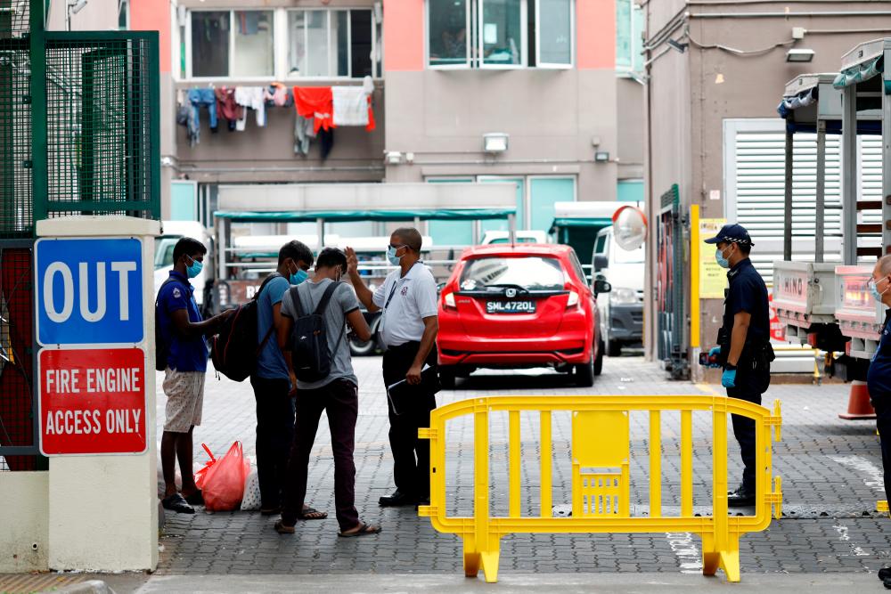 Workers are checked by security and police officers outside the entrance to Westlite Dormitory, one of the two workers’ dormitory gazetted as isolation areas to curb the spread of coronavirus disease (Covid-19) in Singapore on April 6, 2020. — Reuters