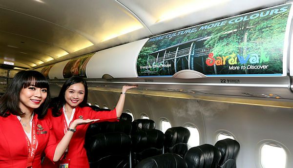 Air Asia flight attendants show off the advertisement promoting tourism in Sarawak, in the flight cabin of and AirAsia passenger jet at Kuching International Airport. — BBXpress
