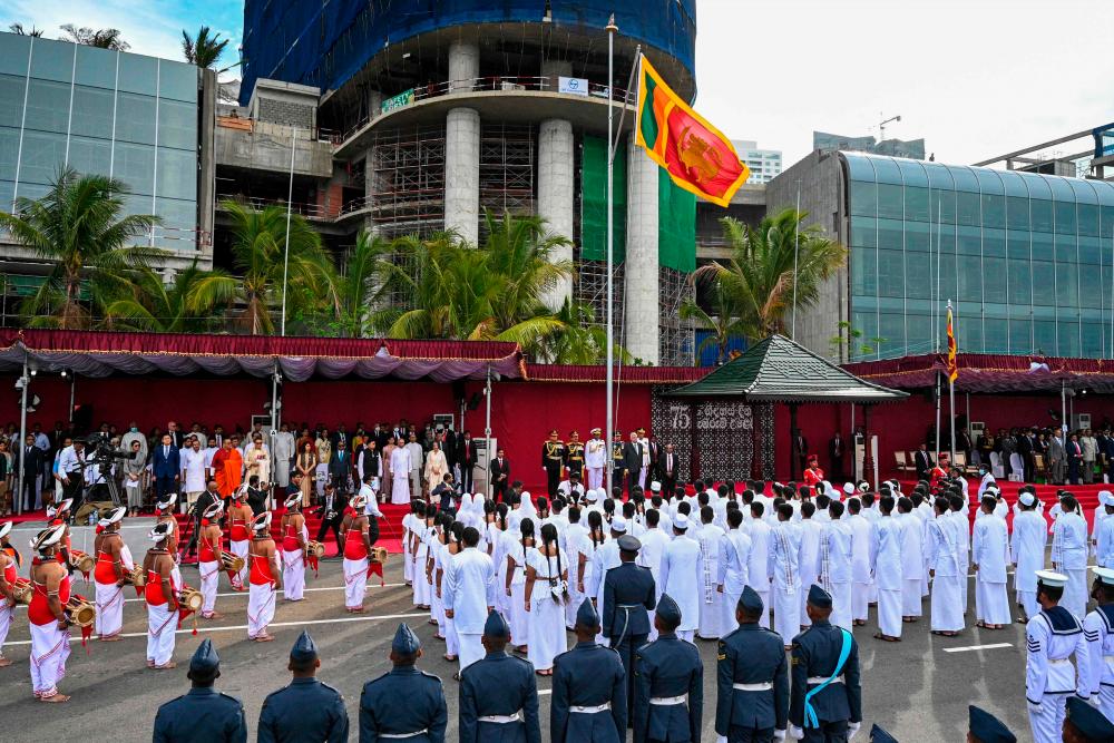 Sri Lanka’s President Ranil Wickremesinghe (on R next to mast) listens to the national anthem during the Sri Lanka’s 75th Independence Day celebrations in Colombo on February 4, 2023. AFPPIX