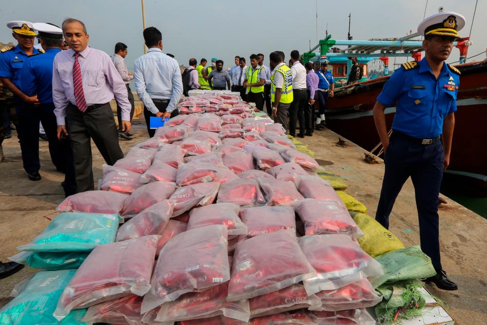 Sri Lanka’s Police Narcotics Bureau officials stand next to packages containing drugs seized by the Sri Lanka Navy at sea, at the Dikkowita Fisheries Harbour off Colombo, Sri Lanka, March 5, 2020. - EPA