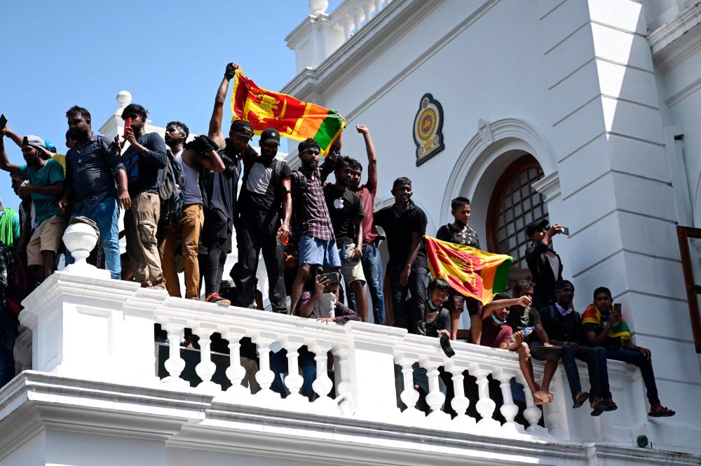 Demonstrators shout slogans and wave Sri Lankan flags from a balcony during an anti-government protest inside the office building of Sri Lanka’s prime minister in Colombo/AFPPix