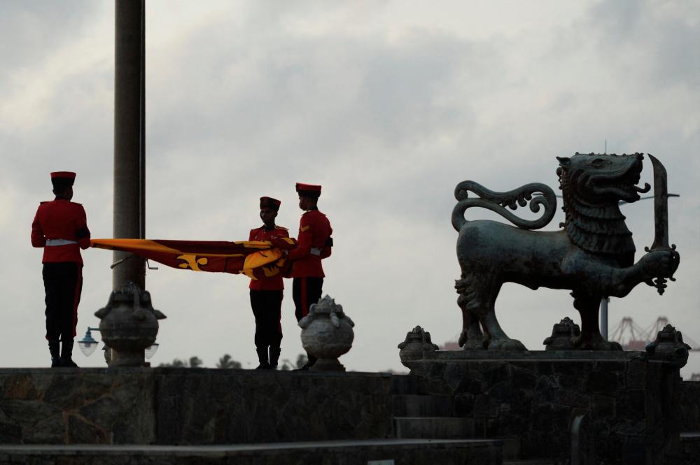 Military personnel in ceremonial uniform lower the Sri Lanka national flag at Galle Face Green in Colombo on July 23, 2022. AFPPIX