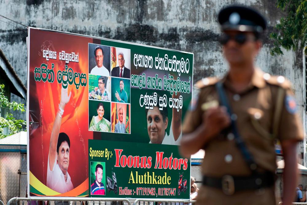 A policeman stands guard at a roadblock near an electoral poster of deputy leader of the ruling United National Party (UNP) and New Democratic Front presidential candidate Sajith Premadasa before a campaign rally in Colombo on November 13, 2019. - AFP