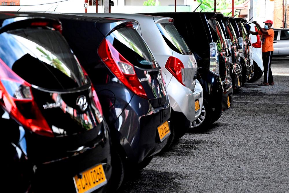 In this picture taken on January 10, 2022, a man washes cars displayed for sale at a car dealership in Malabe, in the district of Colombo. AFPpix