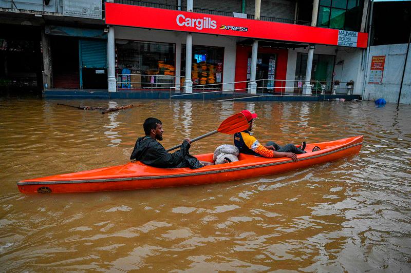 A resident rows a boat through a flooded street after heavy rains in Malwana on the outskirts of Colombo on June 2, 2024. Flash floods, mudslides and falling trees have killed at least 14 people in Sri Lanka as the island nation is battered by monsoon storms, the country’s disaster centre said on June 2. - Ishara S.Kodikara / AFP