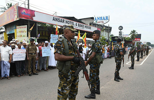 Sri Lankan security personnel stand guard as Sri Lankan Muslims gather after Friday noon prayers to remember the victims and to protest against the terrorist group who was responsible for Easter Sunday suicide attacks that killed 258 people in Sri Lanka, at Masjid Yusufiyah mosque in Negombo on May 24, 2019. — AFP