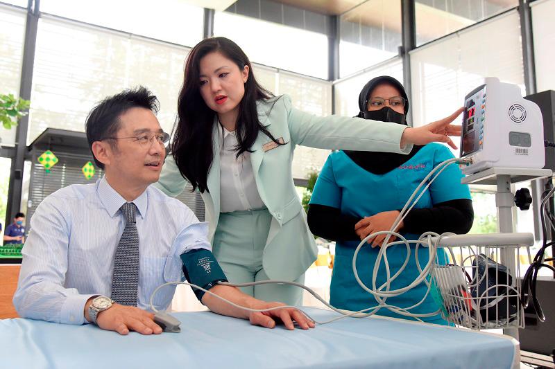 Diana Tan (centre) explains to Ter Leong Yap (left) about his blood pressure reading at the newly launched Sunsuria Care Hub.