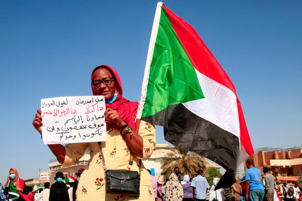 A demonstrator holds a sign reading in Arabic from Omdurman to East Sudan: here is Kasala, here is the Red Sea, our road heads to you, you will rise up and not be alone; during a protest demanding civilian rule in the Sudanese capital's twin city of Omdurman on December 13, 2021. AFPPIX