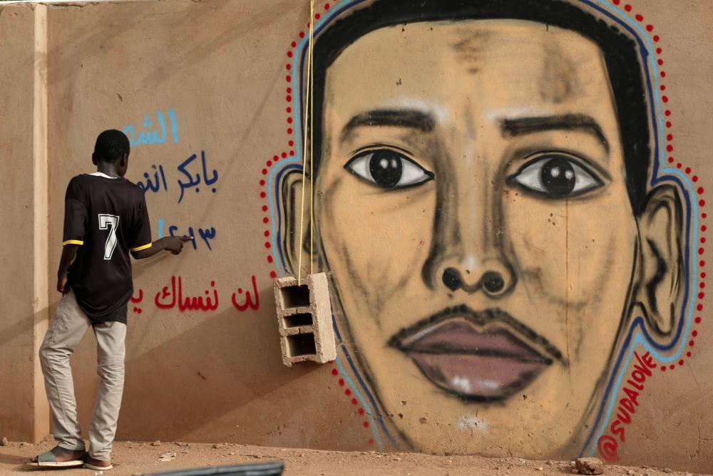 A man walks past the mural painting of Babikir Anwar on the wall of the family home in the neighbourhood of Shambat, in the Sudanese capital Khartoum, on July 21, 2019. — AFP