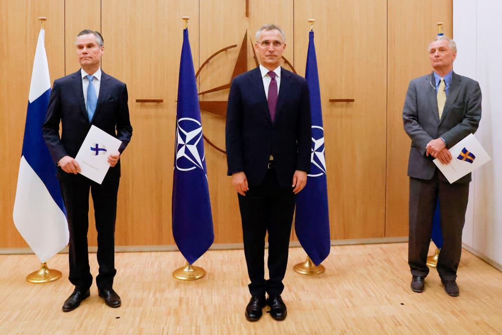 LtoR, Finland’s Ambassador to NATO Klaus Korhonen, NATO Secretary-General Jens Stoltenberg and Sweden’s Ambassador to NATO Axel Wernhoff pose during a ceremony to mark Sweden’s and Finland’s application for membership in Brussels, on May 18, 2022. AFPPIX