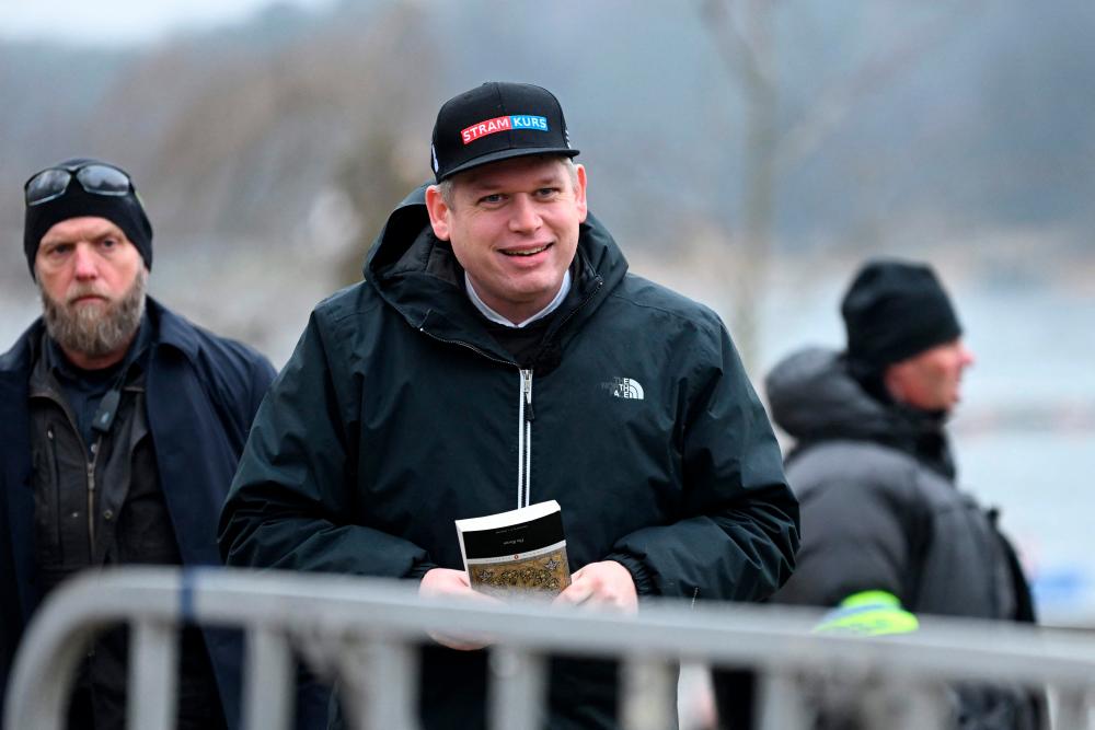 The leader of the far-right Danish political party Stram Kurs, Swedish-Danish politician Rasmus Paludan is pictured while holding The Quran (Koran), the central religious text of Islam, while staging a protest outside the Turkish Embassy in Stockholm, Sweden, on January 21, 2023. AFPPIX