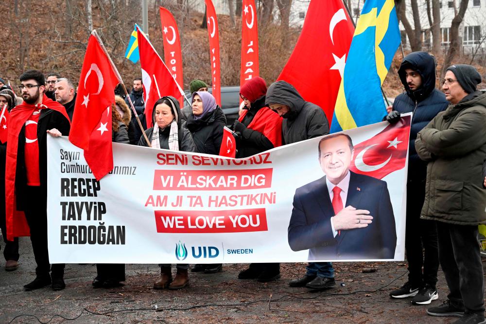 Participants hold Turkish flags and a banner reading ‘Recep Tayyip Erdogan - We love you’ during a demonstration of the pro-Turkish organization Union of European Turkish Democrats (UETD) in support of Turkey and President Recep Tayyip Erdogan outside the Turkish Embassy in Stockholm, Sweden on January 21, 2023. AFPPIX