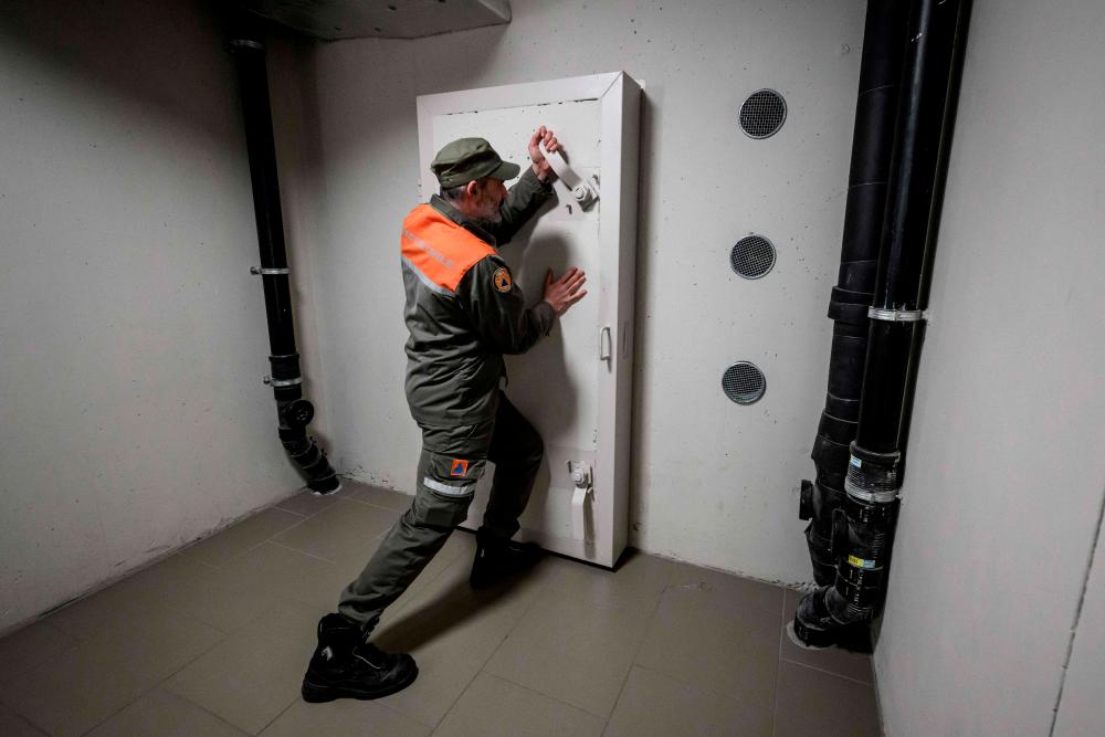 An officer of the Swiss Civil defence of the canton of Geneva closes the door of a private concrete nuclear fallout shelter located underneath a residential building in the city of Meyrin near Geneva on March 25, 2022. AFPPIX