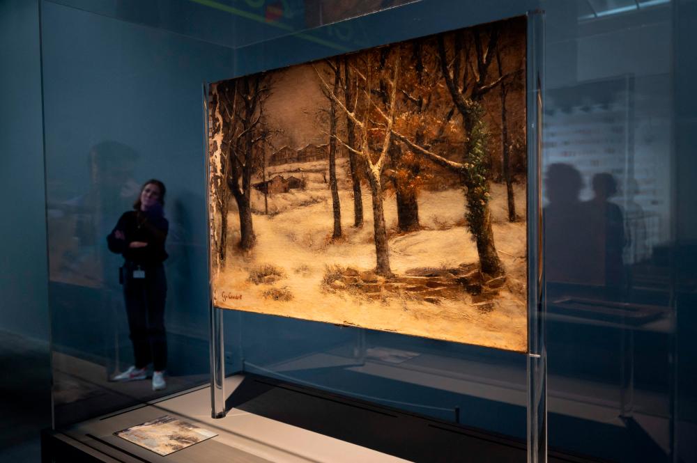 A photograph taken on September 14, 2022, shows an employee walking past a work by Gustave Courbet titled “View of the Ridge Park under the snow, around 1874” ahead of the public opening of the exhibition “Taking Stock, Gurlitt in Review” showing some works of Cornelius Gurlitt’s estate that included works looted from Jews by the Nazis, at the Museum of Fine Arts in Bern. AFPPIX