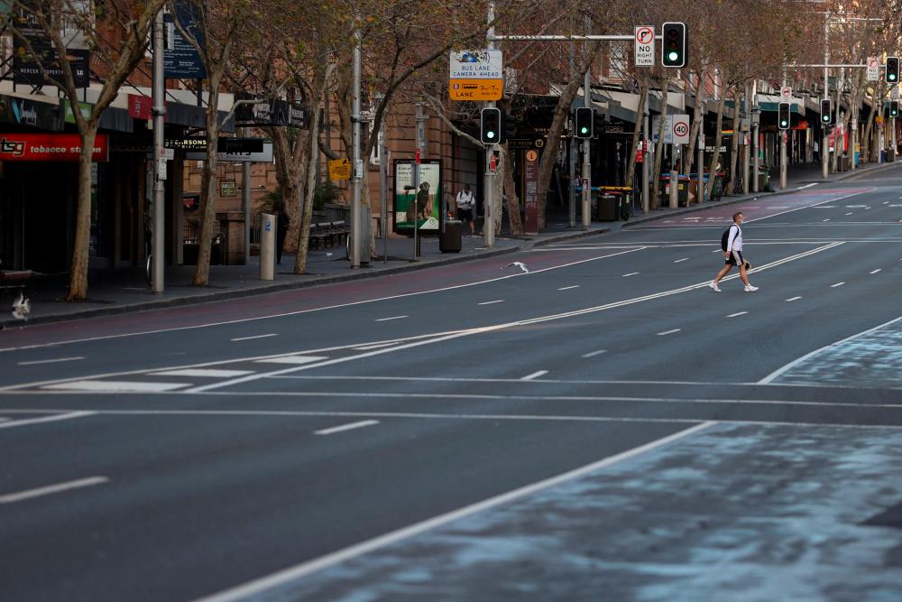 A lone man wearing a protective face mask crosses an empty street during a lockdown to curb the spread of a coronavirus disease (Covid-19) outbreak in Sydney, Australia, July 22, 2021. — Reuters