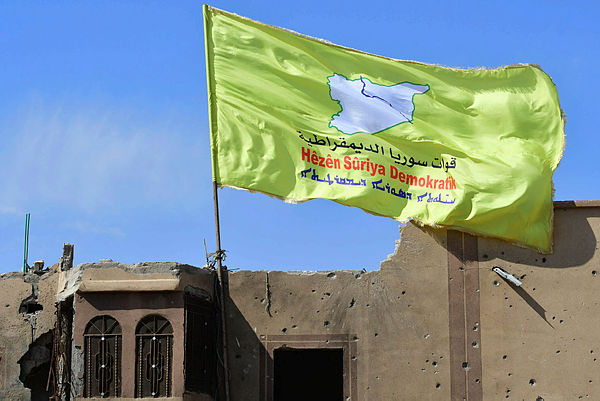 A picture taken on March 23, 2019 shows the US-backed Syrian Democratic Forces’ (SDF) flag atop a building in the Islamic State group’s last bastion in the eastern Syrian village of Baghuz after defeating the jihadist group. — AFP
