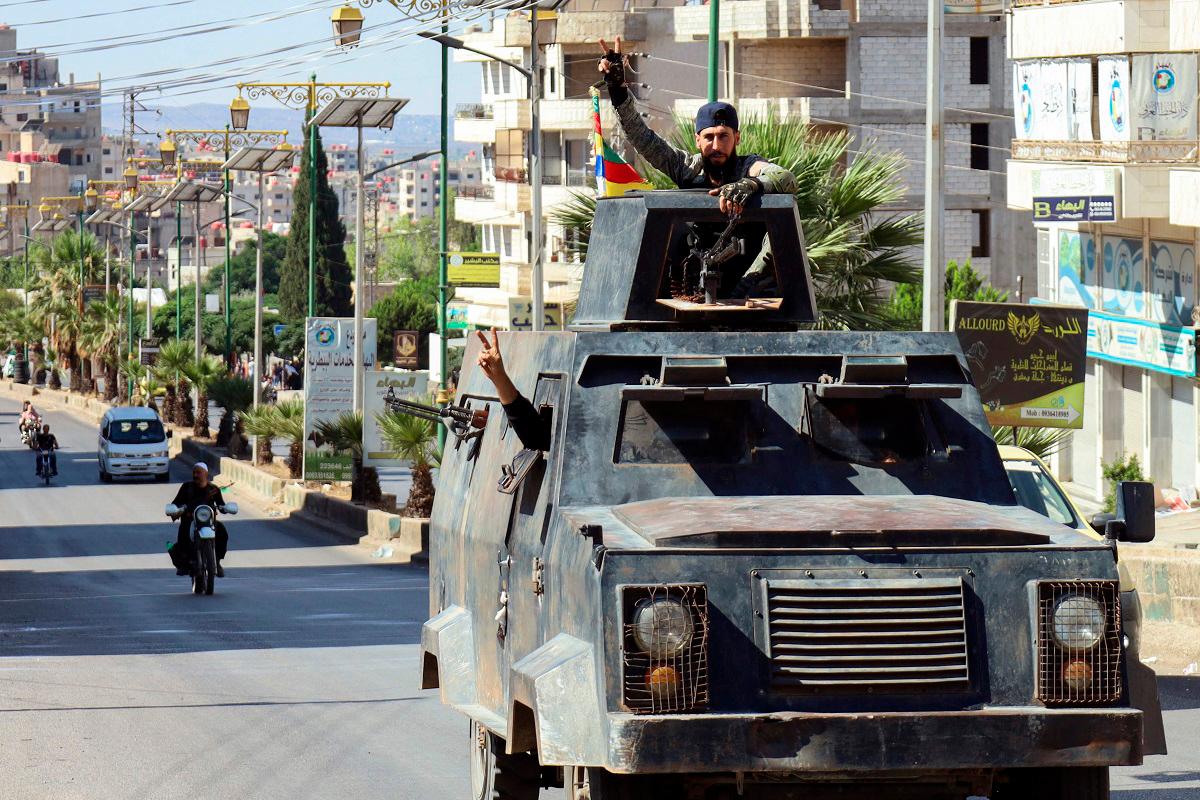 Syrian Druze fighters flash the victory sign as they ride in an armoured vehicle, after Syrian forces pulled out of the southern Sweida governorate, on July 17, 2025. The Druze heartland Sweida has been gripped by deadly sectarian bloodshed since July 13, with hundreds reportedly killed in clashes pitting Druze fighters against Sunni Bedouin tribes and the army and its allies. - Shadi AL-DUBAISI / AFP