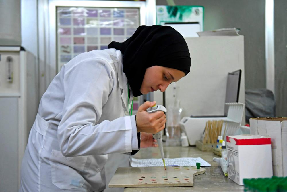 A lab technician works on samples to test for cholera, at a hospital in Syria's northern city of Aleppo on September 11, 2022. - AFPPIX