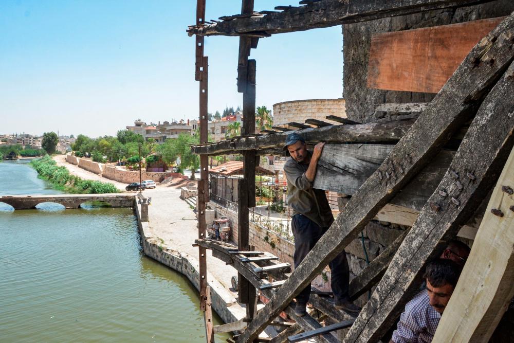 $!Men work on the Mohammadieh Noria (water wheel) along the Orontes (Assi) river in the city of Hama in west-central Syria on June 22, 2020. / AFP / MAHER AL MOUNES