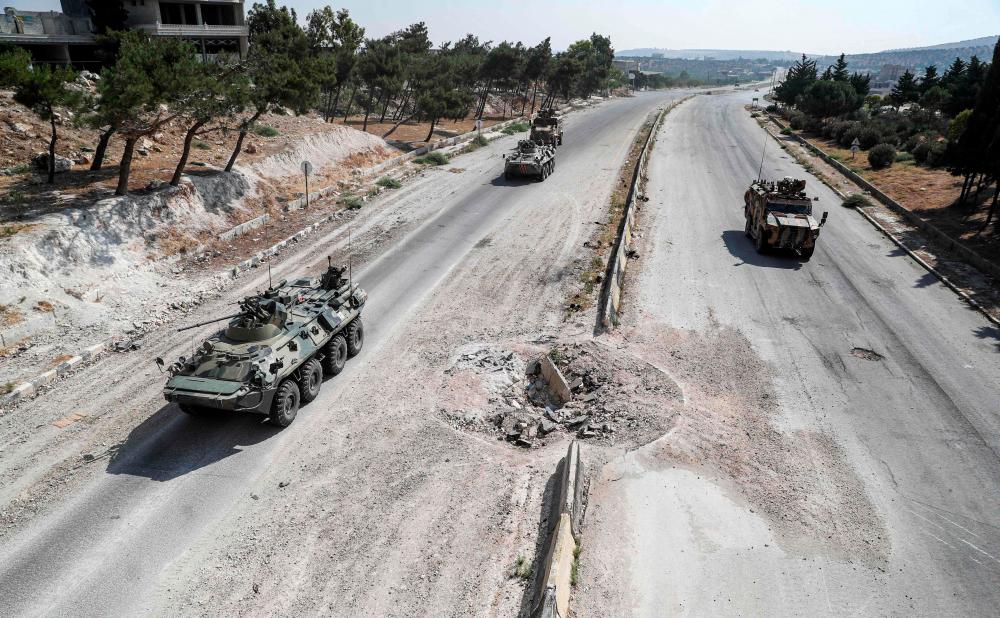 Russian and Turkish military armoured vehicles and armoured personnel carriers (APCs) drive together in a joint patrol along the M4 highway, which links the northern Syrian provinces of Aleppo and Latakia, near Ariha in Syria's rebel-held northwestern Idlib province, on July 7, 2020. — AFP