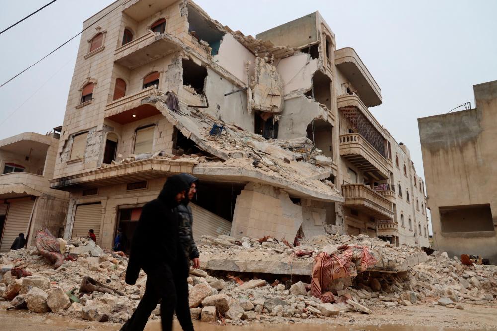 Two men walk past a heavily damaged building following an earthquake in the town of Zardana in the countryside of the northwestern Syrian Idlib province, early on February 6, 2023. AFPPIX