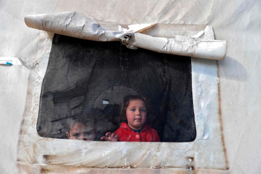 Syrian children look out of the window of a tent window at an emergency shelter in the center of the city of Maarat Misrin, in the rebel-held northern part of the northwestern Idlib province one day after a deadly earthquake hit Syria and Turkey, on February 7, 2023. AFPPIX