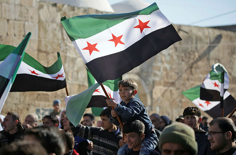 Syrians brandish opposition flags during a demonstration in support of neighbouring Turkey in the town of Bizaa, north of Aleppo on Dec 21, 2018. — AFP