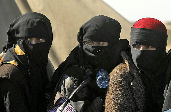 Women wearing niqabs (full face veils) stand in a queue as civilians, who are fleeing from the battered Islamic State-held holdout of Baghouz in the eastern Syrian province of Deir Ezzor, wait to be screened by members of the Syrian Democratic Forces (SDF), before entering into a nearby SDF-held area. — AFP