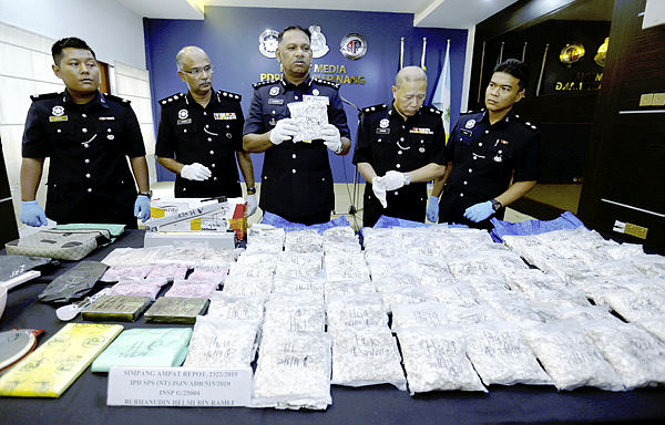 Penang police chief Datuk T. Narenasagaran (center) holding one of the packets of heroin seized.