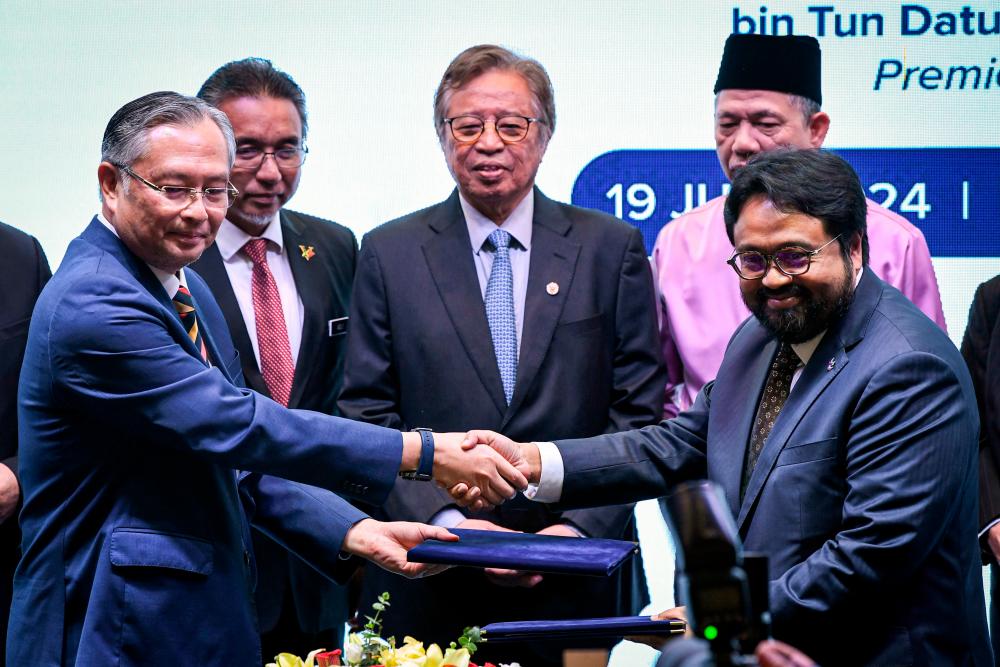 Abang Johari (centre) witnessing the exchange of documents between State Financial Secretary of Sarawak Datuk Seri Dr Wan Lizozman Wan Omar (left) and LTAT chief executive officer Mohammad Ashraf Md Radzi at the MoU signing ceremony on Friday. – Bernamapic