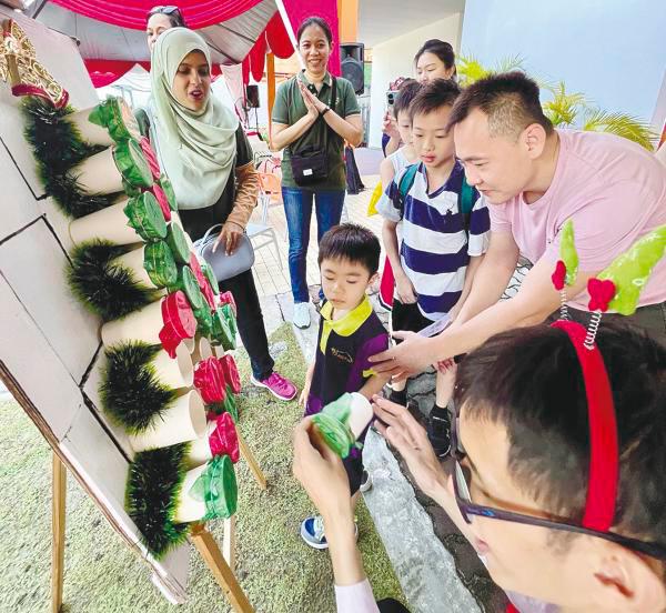 Lim See Kin (right) encouraging his son, Ashton Lim Sung Chuan, at the games station.