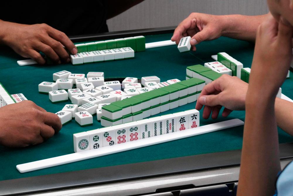 This picture taken on November 12, 2022 shows mahjong players moving their tiles during a round of the game at a parlour in Kaohsiung/AFPPix