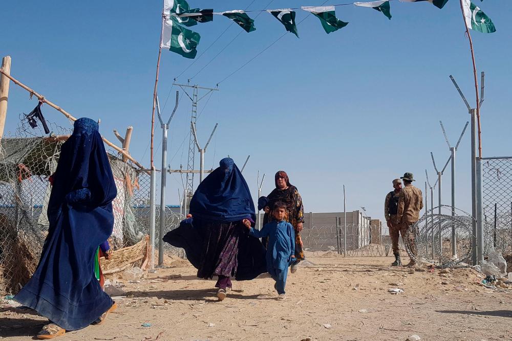 Pakistani soldiers stand guard as stranded Afghan nationals return to Afghanistan at the Pakistan-Afghanistan border crossing point in Chaman on August 14, 2021, after the Taliban took control of the Afghan border town in a rapid offensive across the country. -AFP