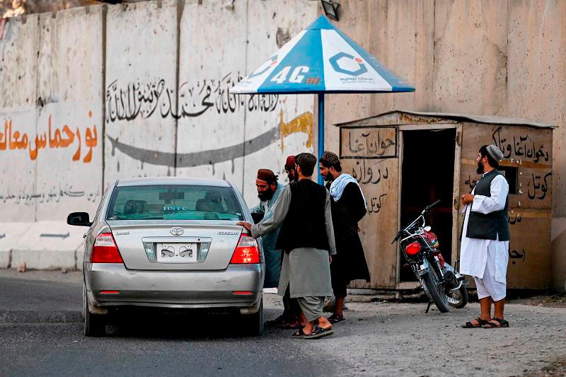 Taliban security personnel inspect a car for security measures at a checkpoint on the outskirts of Kandahar on August 24, 2024. - Wakil KOHSAR / AFP