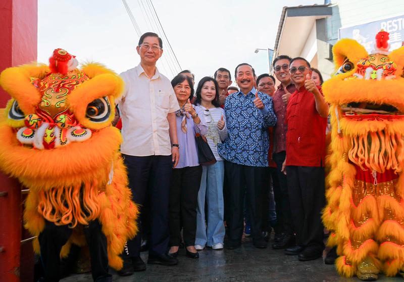 $!Tan and Esther are welcomed to Pulau Ketam by vibrant lion dancers. With them are Lim (left) and Wan (right). THESUN/AMIRUL SYAFIQ