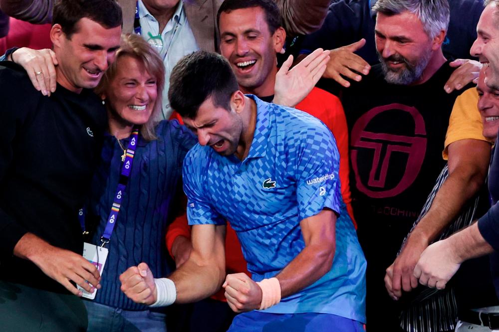 Serbia's Novak Djokovic (C) celebrates victory with his team and relatives including his mother Dijana Djokovic (centre L) and his coach Goran Ivanisevic (centre R) against Greece's Stefanos Tsitsipas during their men's singles final against on day fourteen of the Australian Open tennis tournament in Melbourne on January 29, 2023. AFPPIX